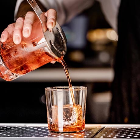Bartender pours negroni