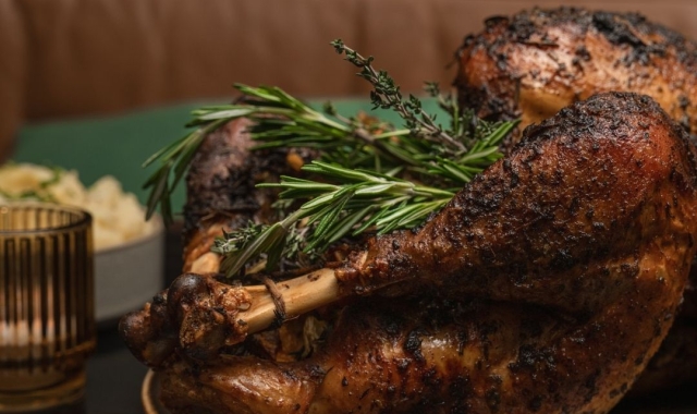 A roasted Thanksgiving turkey sliced and served on a platter with fresh herbs, cranberries, and seasonal garnishes.